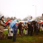 A large crowd gathered on the green in the rain to witness the unveiling of the sign.